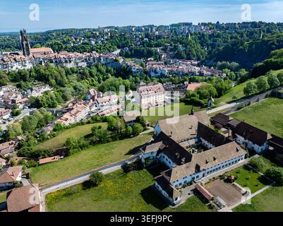 Vista aerea del Monastere de Montorge circondato da prati verdi con lo storico skyline di Friburgo e la Cattedrale di San Nicola sullo sfondo Foto Stock
