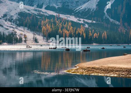 Paesaggio alpino del Lago di Braies con attività nautiche turistiche e pineta autunnale nelle Dolomiti Foto Stock