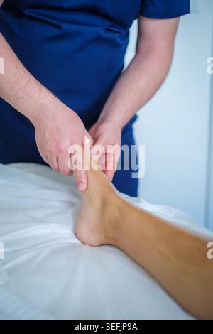 Una donna gode di un rilassante massaggio piedi e gambe con l'olio di un terapista professionista in un tranquillo ambiente spa per il relax e il benessere. Foto Stock