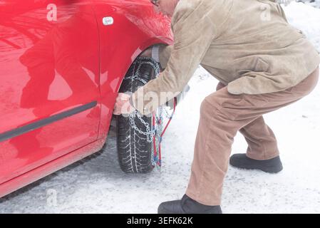indossare catene da neve su un'auto, sicurezza stradale in inverno indossare catene da neve su un'auto Foto Stock
