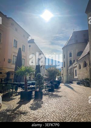 Architettura tradizionale che costeggia un'affascinante strada acciottolata a Bressanone, Trentino alto Adige, offre invitanti cene all'aperto Foto Stock