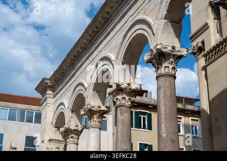 Vista laterale di una galleria di pietra con colonne corinzie nel Palazzo di Diocleziano, Spalato, Dalmazia, Croazia sotto un cielo blu con nuvole. Foto Stock