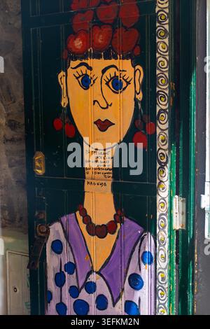 Funchal Madeira 9 maggio 2026 Una porta di legno verde scuro è adornata da un vibrante dipinto stilizzato di una donna Foto Stock