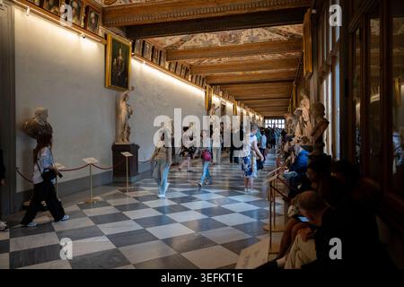 Firenze, Italia - 17 settembre 24: Ampia vista dei visitatori che camminano attraverso un lungo corridoio delle gallerie degli Uffizi a Firenze, Italia, con statue e dipinti Foto Stock