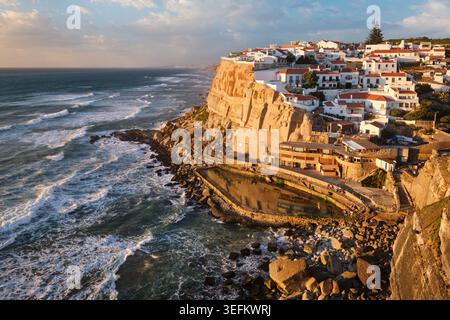 Villaggio sul mare mozzafiato di Azenhas do Mar, arroccato sulle scogliere che si affacciano sull'Oceano Atlantico. Il caldo tramonto proietta un bagliore dorato su questo affascinante hotel Foto Stock