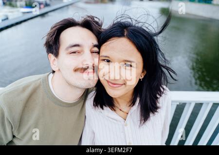 Primo piano ritratto di una felice coppia interrazziale che sorride insieme sul ponte cittadino Foto Stock