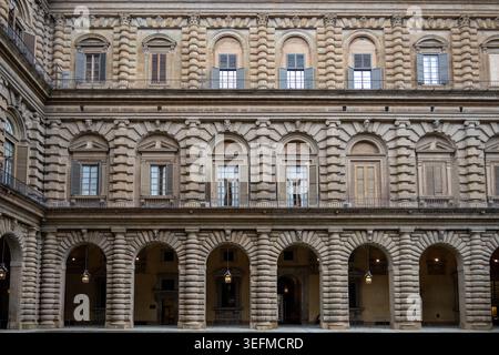 Facciata architettonica con archi in pietra arbustiata e finestre con persiane nel cortile di Palazzo Pitti, Firenze, Toscana, Italia. Foto Stock