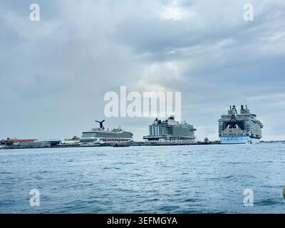 Tre grandi navi da crociera di lusso sono allineate e attraccate al terminal del porto crocieristico di Nassau, Bahamas, sotto un cielo nuvoloso. Foto Stock