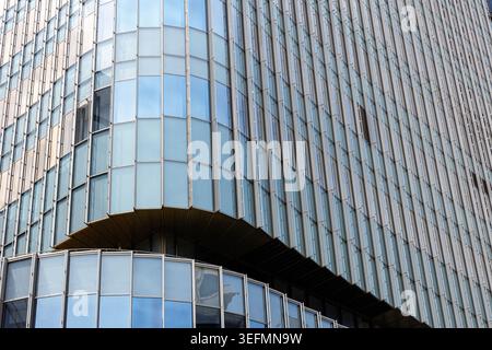Vista ad angolo basso della facciata di un moderno edificio di uffici in vetro con finestre curve e motivi geometrici, sfondo astratto dell'architettura aziendale. Foto Stock