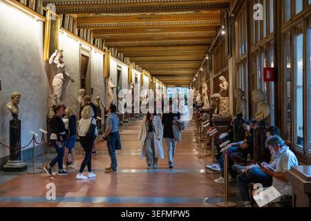 Firenze, Italia - 17 settembre 24: Lungo corridoio museale con statue classiche e visitatori che camminano attraverso le gallerie degli Uffizi, Firenze, Toscana, Italia. Foto Stock