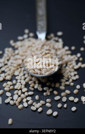 Split Urad dal in Spoon, Macro cibo Angled Top View su sfondi scuri defocati con illuminazione spettacolare Foto Stock