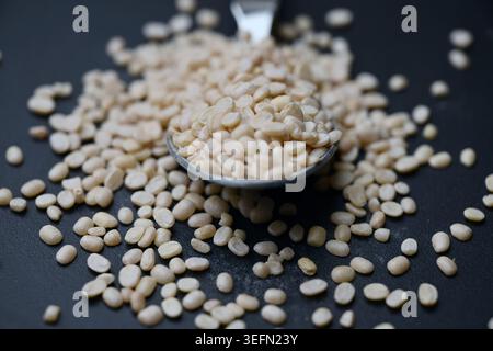 Split Urad dal in Spoon, Macro cibo Angled Top View su sfondi scuri defocati con illuminazione spettacolare Foto Stock