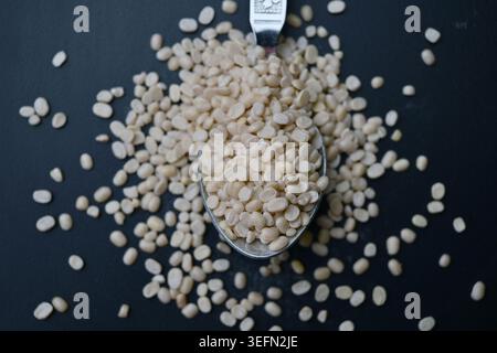 Split Urad dal in Spoon, Macro cibo Angled Top View su sfondi scuri defocati con illuminazione spettacolare Foto Stock