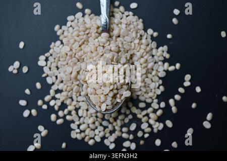 Dividi Urad dal in cucchiaio, Macro Shot con vista dall'alto angolata con sfondi neri sfocati, Fotografia di primo piano degli ingredienti alimentari Foto Stock