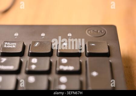 Vista dall'alto angolo primo piano Macro tastiera del computer nera evidenziando il tasto asterisco su sfondi tecnici sfocati Foto Stock