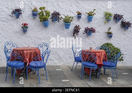 Street Cafe con mobili da esterno blu e vasi di fiori blu su una parete bianca in stile mediterraneo, Mijas, Andalusia, Spagna Foto Stock