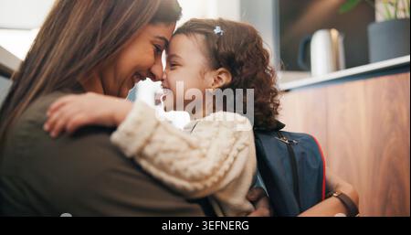 Zaino, abbraccio e madre con il bambino in casa preparandosi per l'asilo, il saluto o lo sviluppo. Felice, famiglia e ragazza che abbraccia mamma per Foto Stock