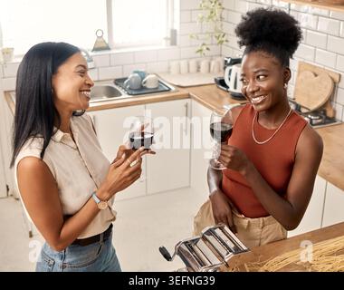 Vino, cucina e amici in cucina per conversazione, pasta e connessione a casa. Unione, bevande e donne con bicchiere di champagne per socializzare Foto Stock