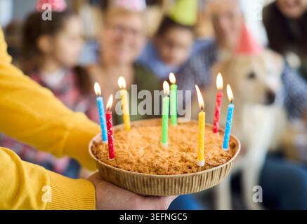 Primo piano torta di compleanno con candele alla festa di famiglia in un'accogliente casa multigenerazionale Foto Stock