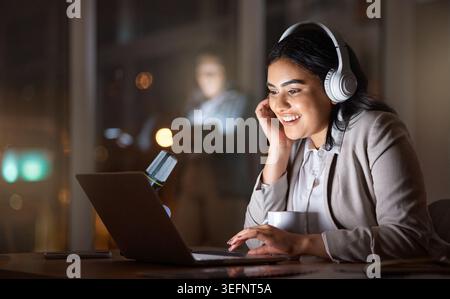 Streaming, laptop e donna in ufficio con cuffie, tracce audio o sito audio durante il turno di notte. Digitale, sorriso o dipendente sul posto di lavoro con la tecnologia Foto Stock
