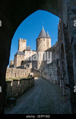 21 febbraio 2026. Ammira attraverso un arco in pietra dello Chateau Comtal e le mura difensive nella cittadella medievale di Carcassonne, Occitanie, Francia, u Foto Stock