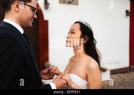 Sposa e sposo interrazziale che guardano con amore, celebrando il giorno del loro matrimonio Foto Stock