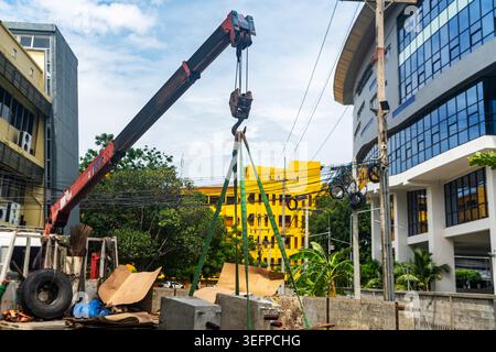 Un cantiere molto trafficato è caratterizzato da una grande gru che opera in mezzo a strutture di costruzione parziali, attrezzature di sicurezza e materiali da costruzione in blu S. Foto Stock
