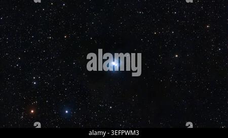 Osserva una nebulosa riflessa blu brillante illuminata contro la distesa oscura cosmica. Numerose stelle bianche e arancioni brillano nel profondo cielo nero Foto Stock