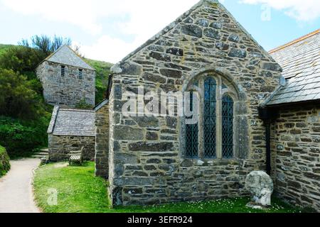 Chiesa medievale di San Winwaloe a Gunwalloe con il suo campanile indipendente del XV secolo con un'antica croce celtica in primo piano. Foto Stock