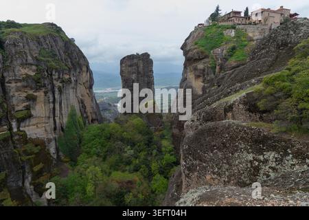 Una suggestiva vista di un solitario pilastro di arenaria al centro, con il Sacro Monastero di Varlaam arroccato sulle alte scogliere a destra. Foto Stock