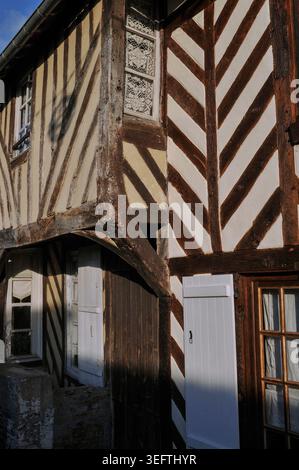 Intricata cortina di pizzi in stile tradizionale Normandia copre la finestra nell'antica casa in legno a Beuvron-en-Auge, a Pays d'Auge, Calvados, bassa Normandia, Francia. Beuvron, un tempo di proprietà della famiglia anglo-francese Harcourt, ha residenze e case ben conservate con cornici in legno risalenti al XVI-XVIII secolo. Scelto come uno dei più bei villaggi della Francia. Foto Stock