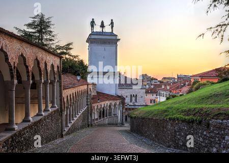Tramonto su Udine, in Italia, scendendo dalla collina del Castello con la Torre dell'Orologio di San Giovanni Foto Stock
