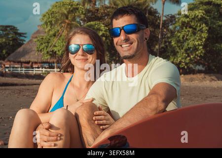 Emozioni autentiche e una vera chimica brillano in questo primo piano. Le strutture del tetto in paglia e la lussureggiante vegetazione sullo sfondo suggeriscono un Foto Stock