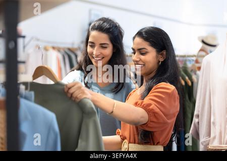 Due giovani donne eleganti che selezionano insieme i vestiti in una boutique moderna Foto Stock