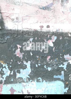 Primo piano di una parete urbana intemprata con vernice sbucciata, strati incrinati e superfici scheggiate in nero, rosa e turchese, una texture illuminata dal sole che rivela un effetto co Foto Stock