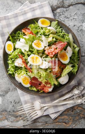 Insalata a basso contenuto di carboidrati con uova di quaglia, pancetta, mozzarella e insalata mista in un piatto sul tavolo. Vista dall'alto verticale Foto Stock