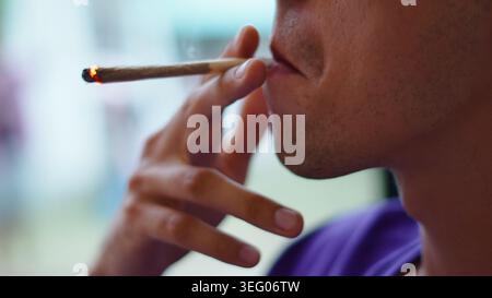 Persona che espone fumo da un'articolazione di marijuana illuminata, che consuma cannabis Foto Stock