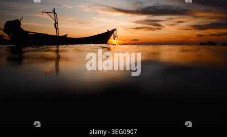 Barca a coda lunga sagomata al tramonto di koh tao, tranquilla scena serale sull'acqua Foto Stock