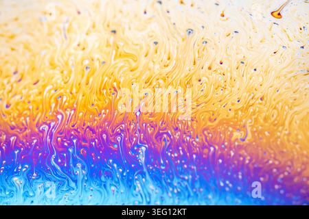 Vista ravvicinata della superficie di una bolla di sapone che mostra fenomeni di interferenza e colori vorticosi come giallo, arancione, viola e blu Foto Stock