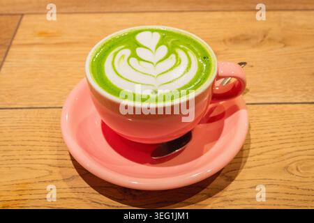Tè verde matcha con decorazione floreale in schiuma in tazza porcellana rosa sul tavolo presso la caffetteria in Giappone. Foto Stock