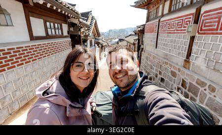 I turisti sorridono per un selfie allo storico villaggio Bukchon Hanok di Seoul, Corea del Sud. La tradizionale architettura coreana si allinea con le affascinanti strade di Foto Stock