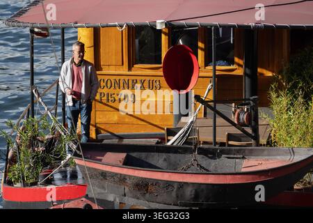 Uomo in piedi sul ponte di una casa galleggiante sulla Senna a Parigi, in Francia. Foto Stock
