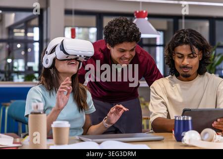 Donna asiatica in uniforme blu che parla al telefono mentre scrive i moduli alla scrivania dell'ufficio con la targa Foto Stock