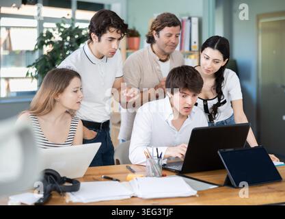 Colleghi che guardano insieme un notebook in ufficio Foto Stock