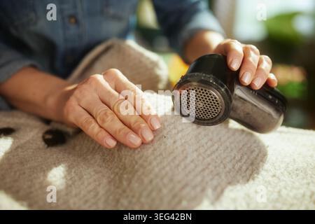 Una donna utilizza un rasoio per tessuti per ripristinare un indumento dalla texture colorata, assicurandosi che rimanga in perfette condizioni per la prossima stagione. Foto Stock