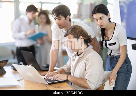 Colleghi che guardano insieme un notebook in ufficio Foto Stock