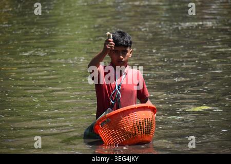 Un giovane mostra un pesce pescato su un cesto di vimini durante l'antico Panzath Fish Festival. L'evento annuale della comunità si raddoppia come uno sforzo vitale per la conservazione, dove i residenti ripuliscono il limo dalle sorgenti storiche per garantire acqua pulita per l'irrigazione prima della stagione di piantagione del riso. Il 17 maggio 2026 a Qazigund, nel Kashmir meridionale. (Immagine di credito: © Danish Showkat/eyepix via ZUMA Press Wire) SOLO PER USO EDITORIALE! Non per USO commerciale! Foto Stock