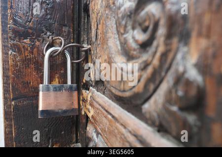 Il vecchio lucchetto sulla porta di legno mostra segni di usura e utilizzo Foto Stock