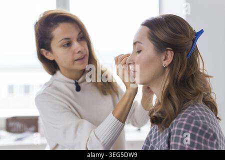 Bellezza e cosmesi concetto - Makeup artista facendo professionale compongono di giovane donna Foto Stock