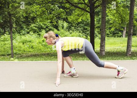 Una giovane donna che si prepara per una corsa in pista Foto Stock